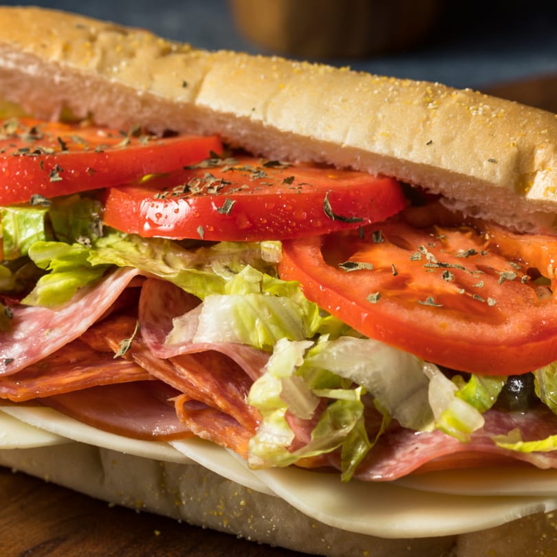 Close-up of a delicious Italian sub sandwich with salami, ham, cheese, lettuce, and tomatoes.